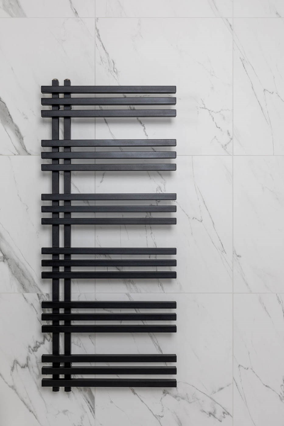 Radiator replacement: Black towel radiator with white marble effect tiles