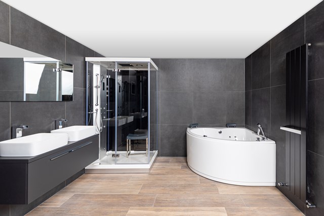 wellness-badkamer-stoomcabine-whirlpool.jpg Moderne badkamer met zwarte meubels, dubbele wastafels, glazen douchecabine en een hoekbad in wit acryl.