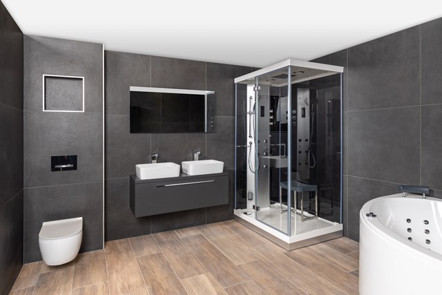 Moderne Badezimmer mit gläserner Kabinendusche, Doppelwaschbecken und freistehender Badewanne, grauen Fliesen und Holzboden.