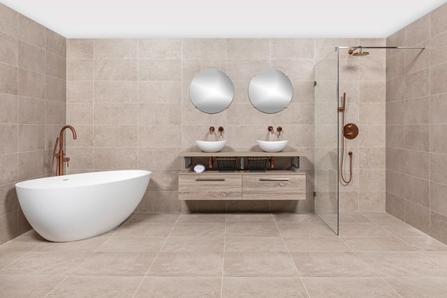 Luxe moderne badkamer met vrijstaand wit bad, inloopdouche met glazen wand en dubbele wastafelset in natuursteen.