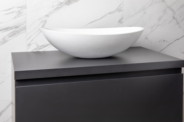 White Oval basin made of ceramic on a matt grey bathroom cabinet, ideal for a modern bathroom style.