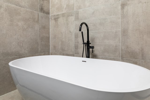 Vrijstaand wit ovalen bad, modern design, zwarte kraan, ideaal als eyecatcher in een luxe badkamerinterieur.