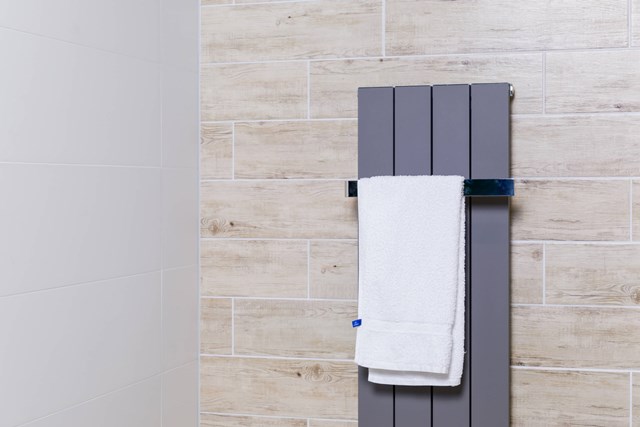 Grijze verticale designradiator met handdoekrek, modern en strak, ideaal voor stijlvolle badkamerverwarming.