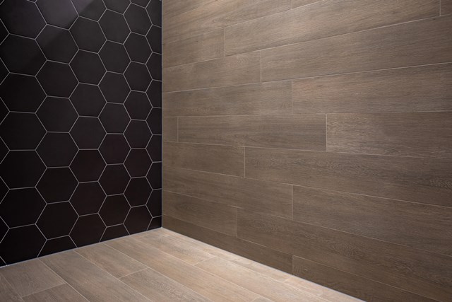 Houten badkamertegel in bruine tint met hexagon zwarte accentwand; moderne keramische afwerking voor stijlvolle badkamerruimtes.