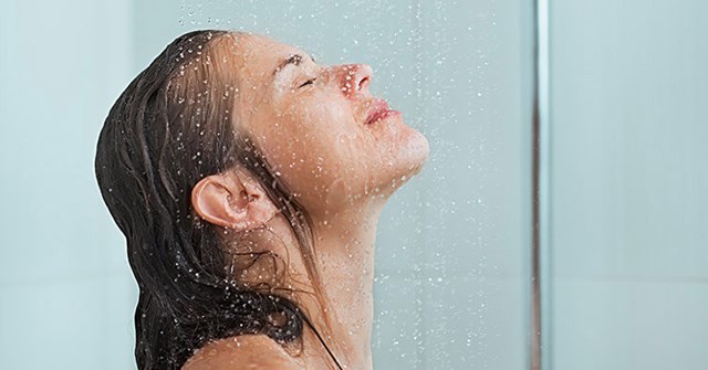 Duschkopf mit Wasserstrahl in modernem Badezimmer, glänzendes Chrom-Design und gläserne Duschwand im Hintergrund.