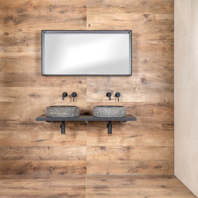 Dubbele wastafelset met grijze natuurstenen kommen, zwarte kranen en houten achterwand, perfect voor een moderne badkamer.