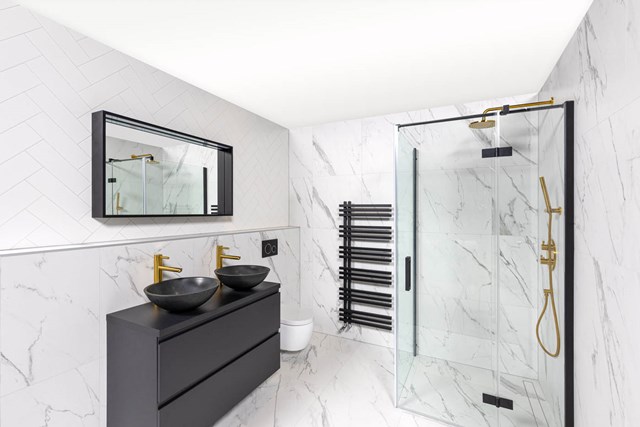 Moderne badkamer met marmeren wanden, zwarte wastafelmeubels, dubbele zwarte waskom en glazen douchecabine met regendouche.