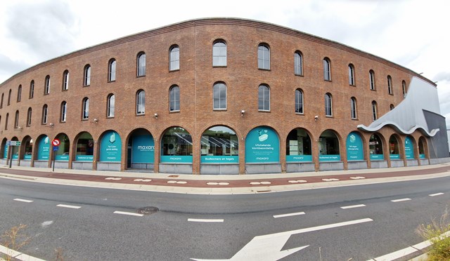 Roodbruine bakstenen gebouw met boogramen, moderne architectuur, geen product zichtbaar of badkamerrelatie te zien.