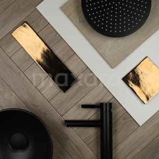 Modern black basin taps and matte black shower head on a wooden bathroom tile with gold accents.