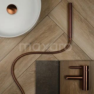Koperkleurige badkamerkraan en flexibele slang op houtlook tegelvloer met witte wastafel; modern design.