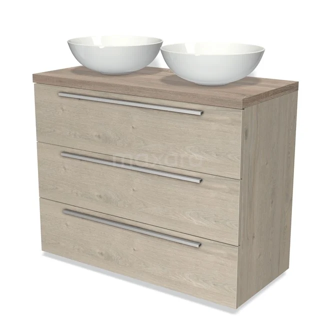 Wooden bathroom unit with drawer fronts in light oak colour, fitted with two white countertop wash basins and chrome handles.